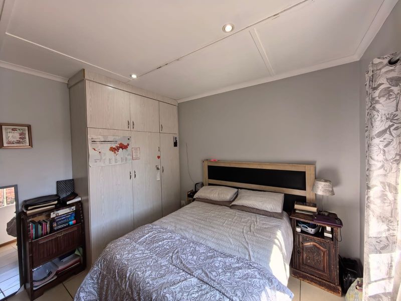 A functional bedroom featuring built-in wardrobes, tiled flooring, and recessed downlighting, offering a neutral base for personalization.