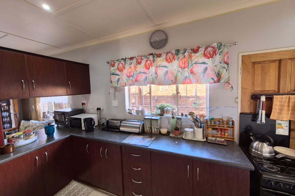 A functional kitchen featuring dark wood cabinetry, laminate countertops, tiled flooring, and a built-in stove, offering a practical layout for daily meal preparation.