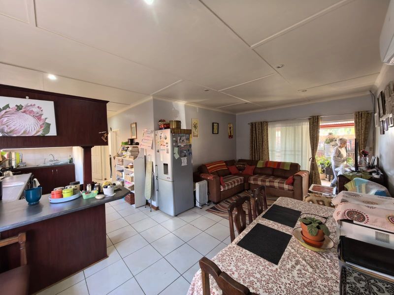 Open-plan living, dining, and kitchen area featuring tiled flooring, built-in cabinetry, and direct access to the outdoor patio through a sliding glass door.