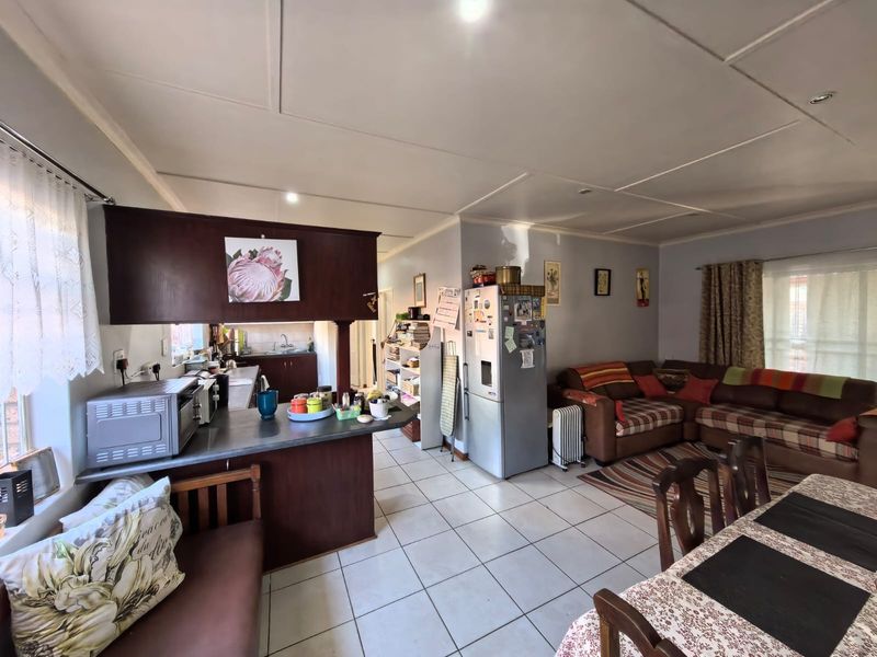 Open-plan living and kitchen area featuring tiled flooring, a breakfast bar, and functional cabinetry, offering a versatile space for daily living.