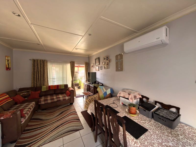 Open-plan living and dining area featuring tiled flooring, a wall-mounted split-system air conditioner, and direct access to an outdoor space via a sliding door.
