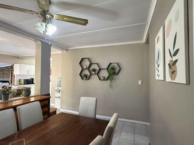 Open plan dining and kitchen area featuring tiled flooring, neutral wall tones, and a ceiling fan, creating a functional and connected living space.
