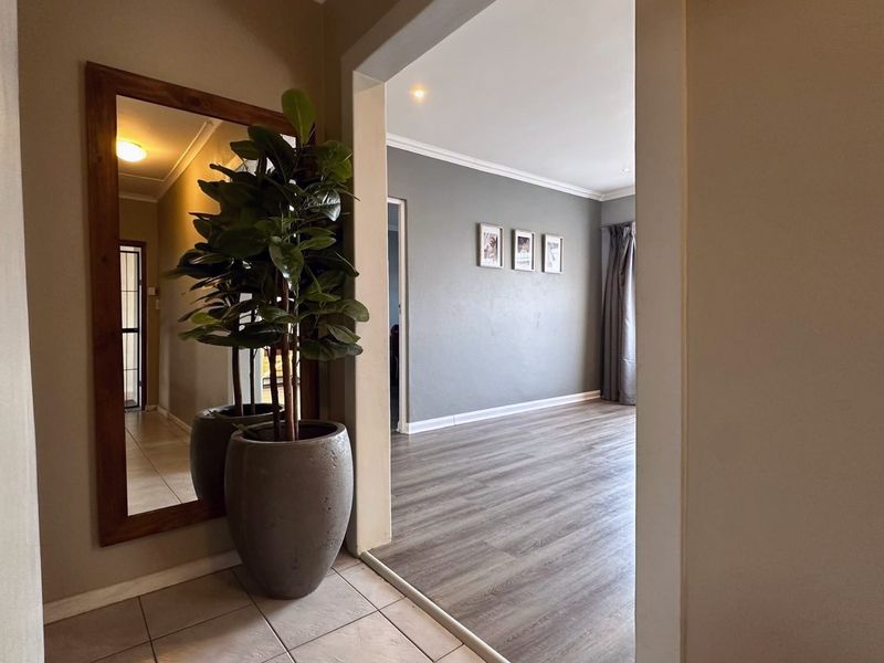 An inviting entrance hall featuring tiled flooring that transitions into a spacious living area with modern laminate wood flooring and neutral wall tones.