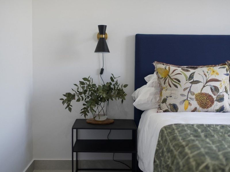 A well-maintained bedroom featuring a modern wall-mounted light fixture and neutral wall finishes.