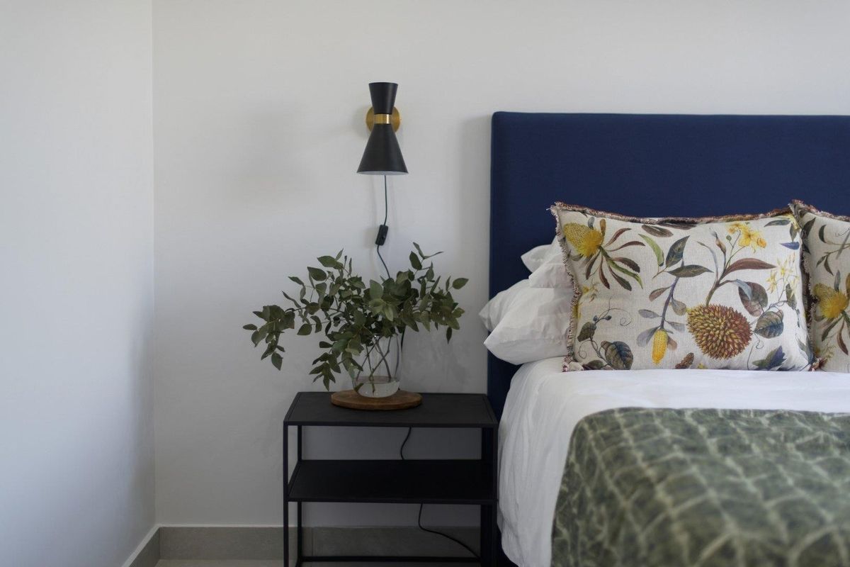 A well-maintained bedroom featuring a modern wall-mounted light fixture and neutral wall finishes.