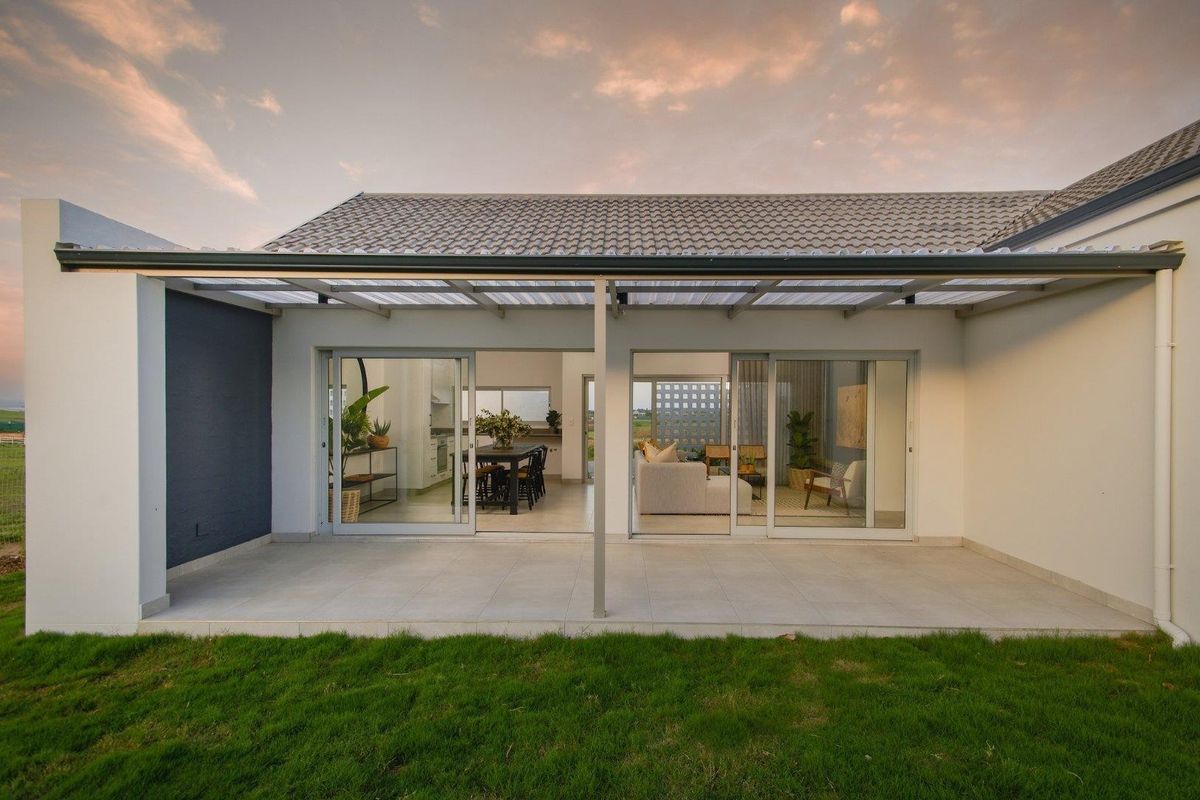 A well-maintained rear exterior view featuring a covered tiled patio with sliding glass doors leading into the open-plan living and dining area.