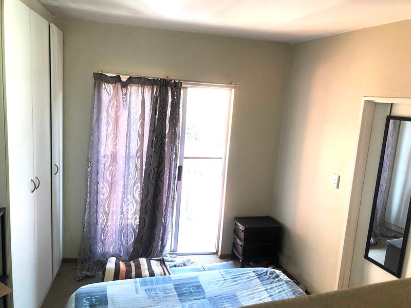 A bedroom featuring built-in cupboards and a sliding glass door providing access to an outdoor area.
