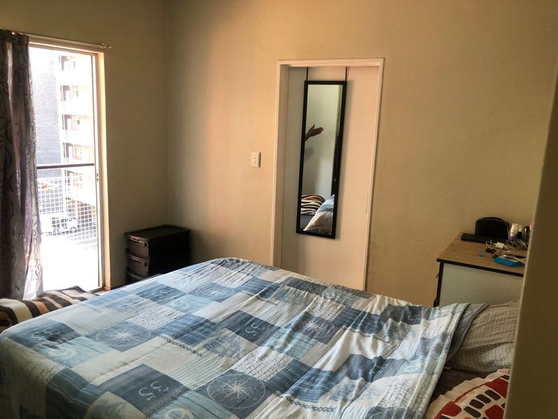 A functional bedroom featuring a sliding glass door that provides access to a balcony, allowing for natural light and ventilation.