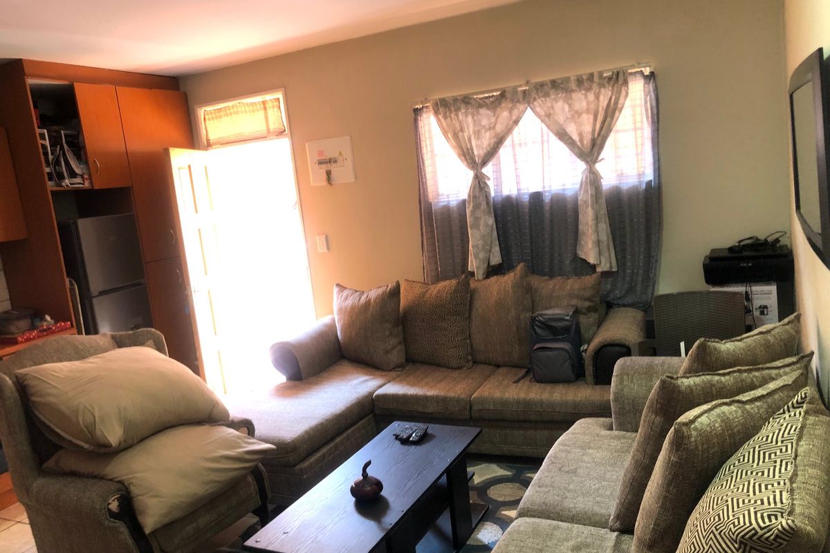 A living room area featuring built-in cabinetry and natural light through a window with security bars.