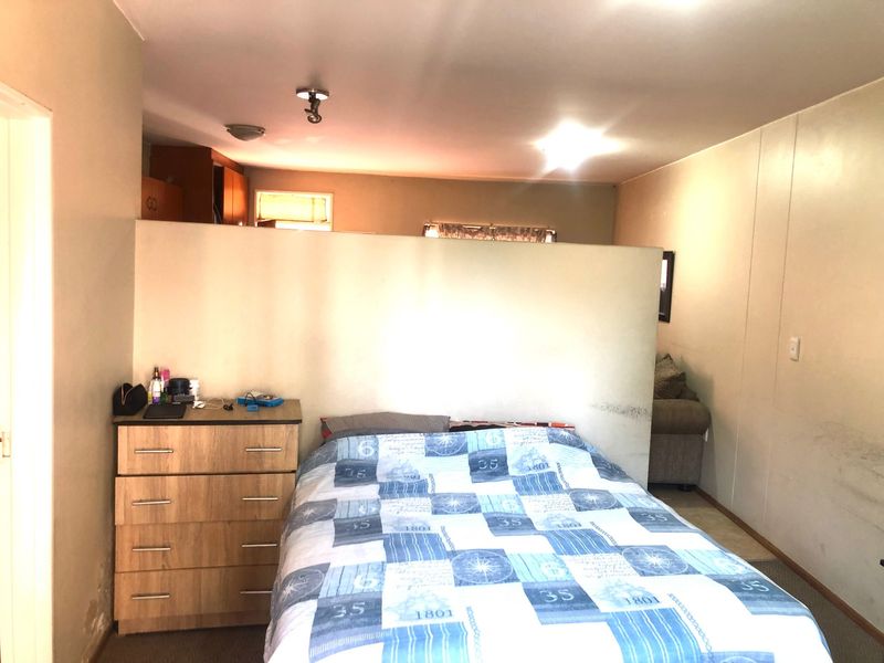 A bedroom featuring a central partition wall, showing signs of wear on the walls and flooring, suitable for cosmetic updates.