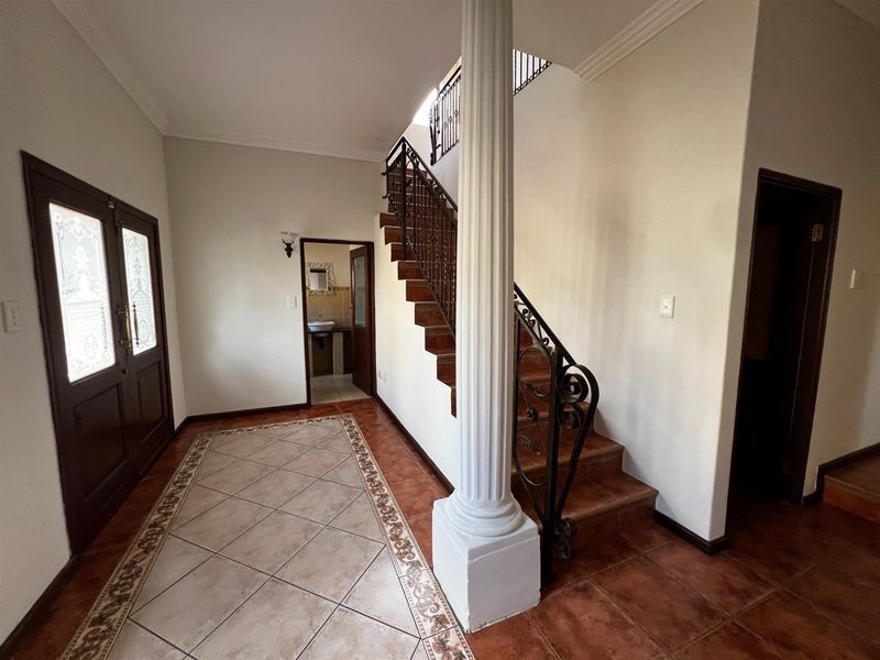 Spacious entrance hall featuring a decorative column, wrought iron staircase railing, and tiled flooring, providing a welcoming transition into the home.