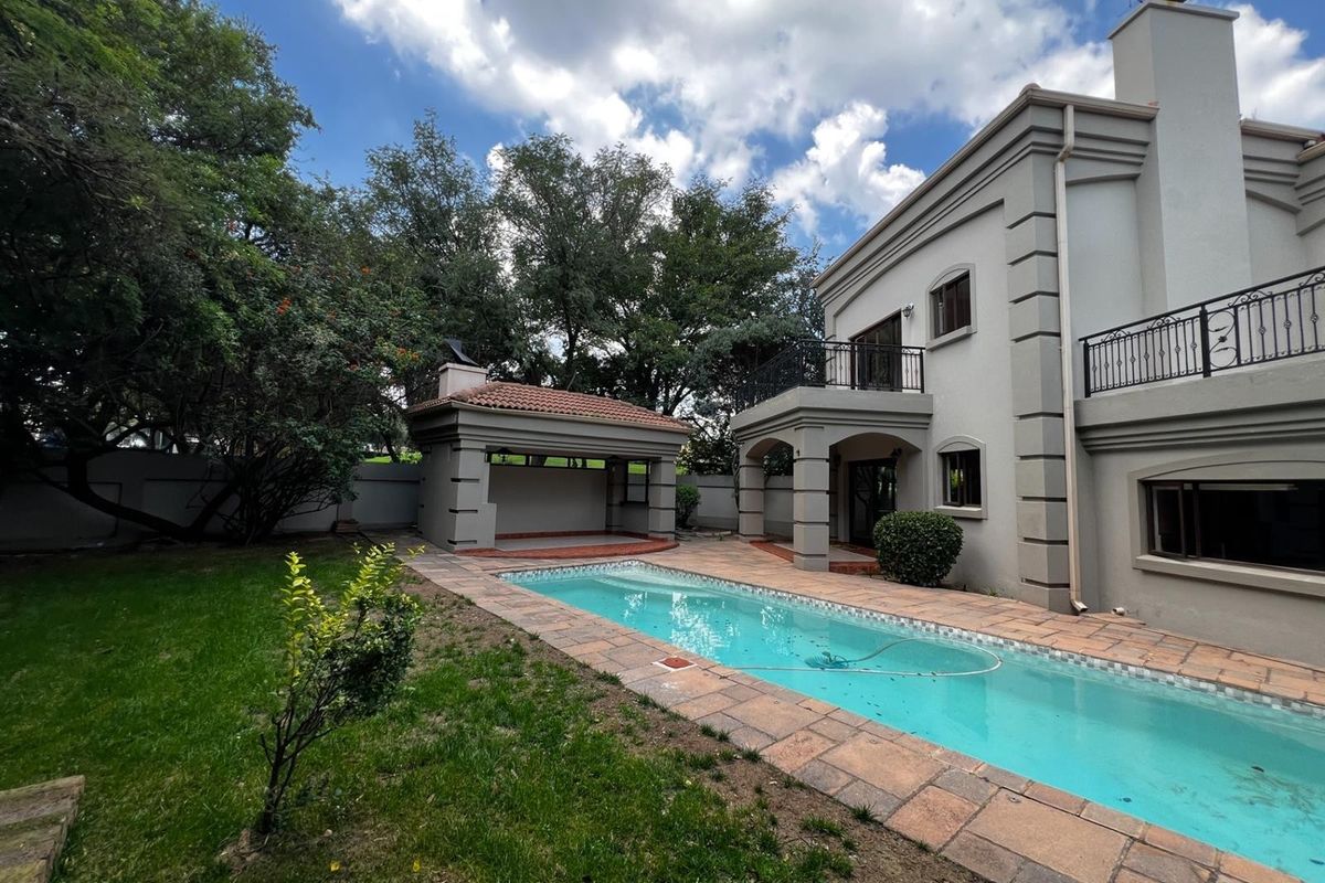 Rear exterior view featuring a swimming pool, paved surround, covered patio area, and a two-story house facade with a balcony.