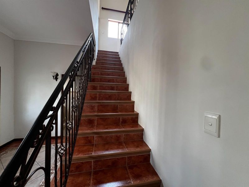 A staircase featuring tiled steps and a decorative wrought iron balustrade leading to an upper level.