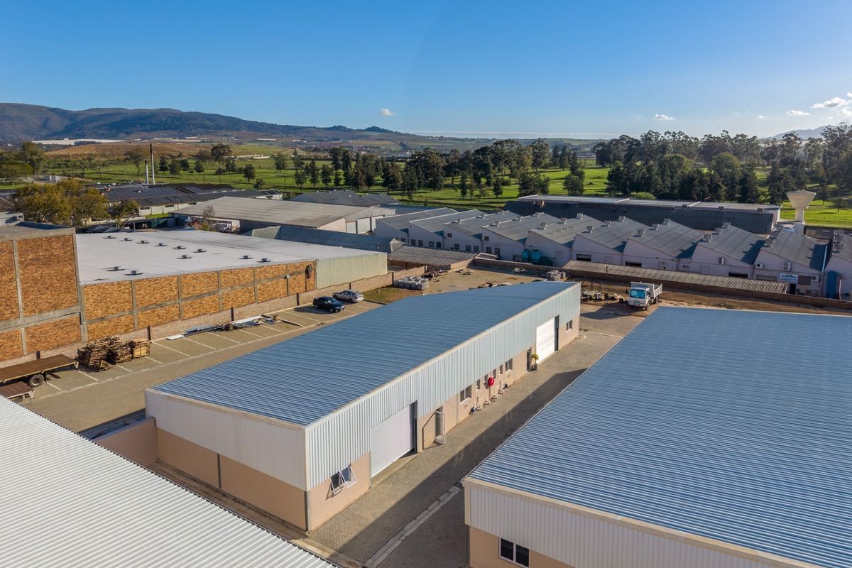 Aerial view of an industrial complex featuring multiple warehouse units with metal roofing, roller shutter doors, and paved access areas.