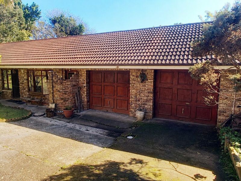 Front elevation of a single-story brick house featuring a tiled roof, double garage with timber doors, and a concrete driveway.