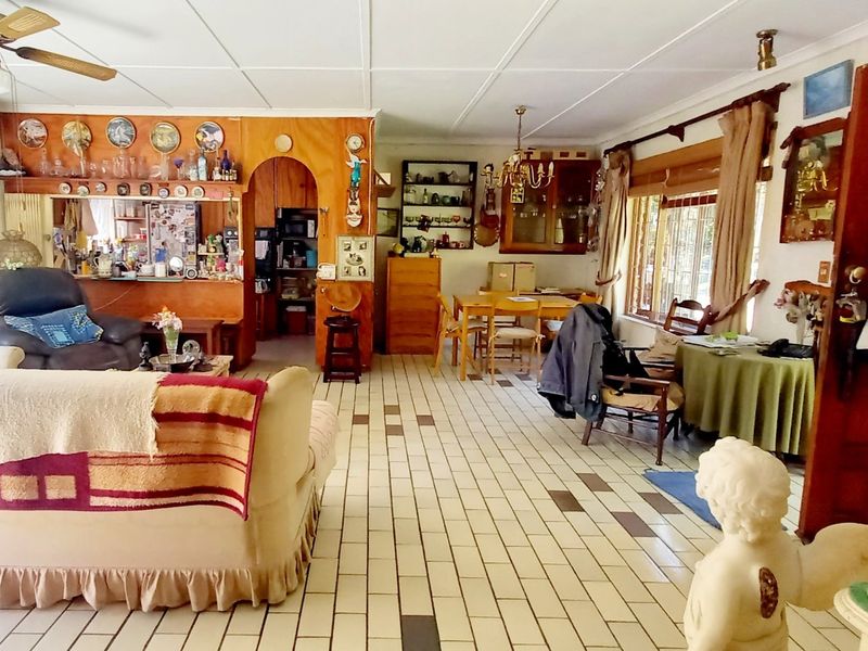 Spacious open-plan living and dining area featuring tiled flooring, a ceiling fan, and an arched entryway leading to the kitchen area.