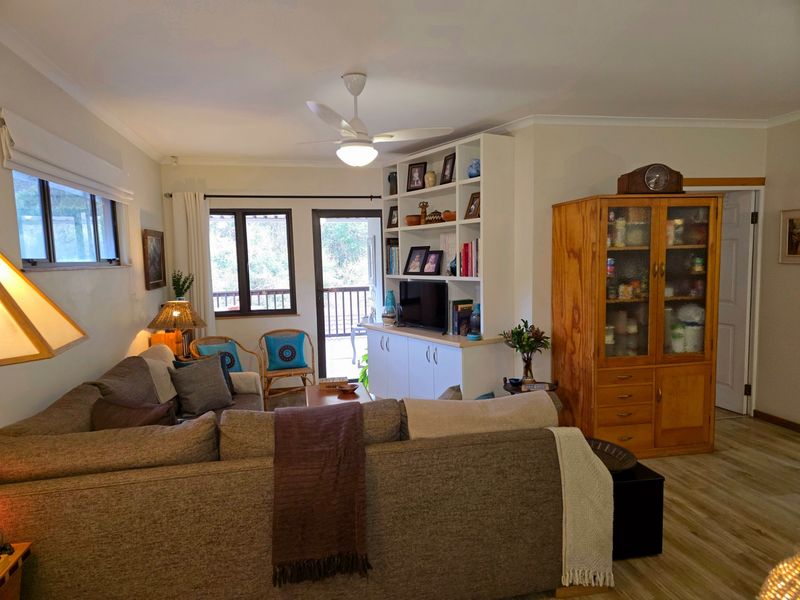 A comfortable living room featuring built-in shelving and cabinetry, a ceiling fan, and direct access to an outdoor balcony area.