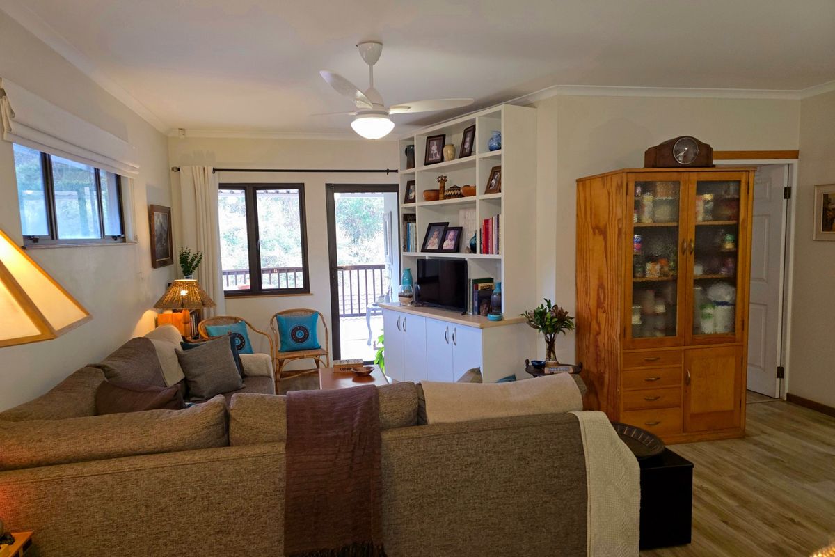 A comfortable living room featuring built-in shelving and cabinetry, a ceiling fan, and direct access to an outdoor balcony area.