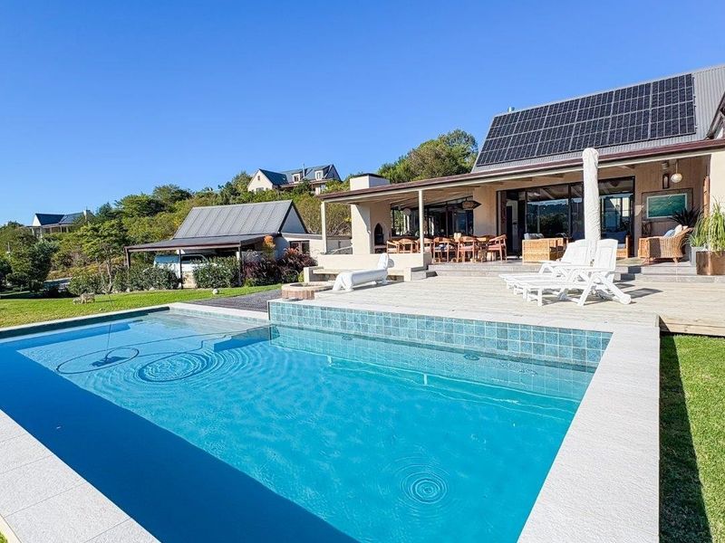 A well-maintained swimming pool with tiled coping, adjacent to a spacious timber deck and covered patio area, featuring solar panels on the roof.