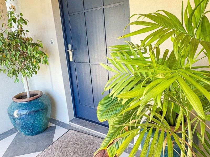 A clean and well-maintained entrance area featuring a modern dark blue panelled front door and geometric tiled flooring.