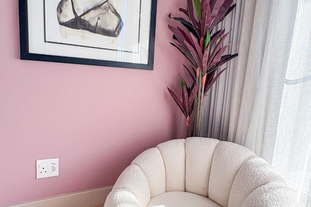 A cozy corner featuring timber flooring, pink painted walls, and a modern electrical power outlet.