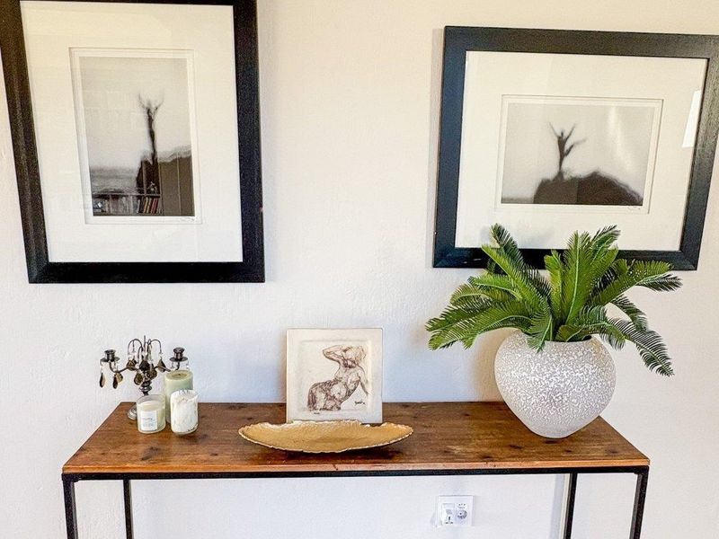 A close-up view of a wall featuring a console table and framed artwork.