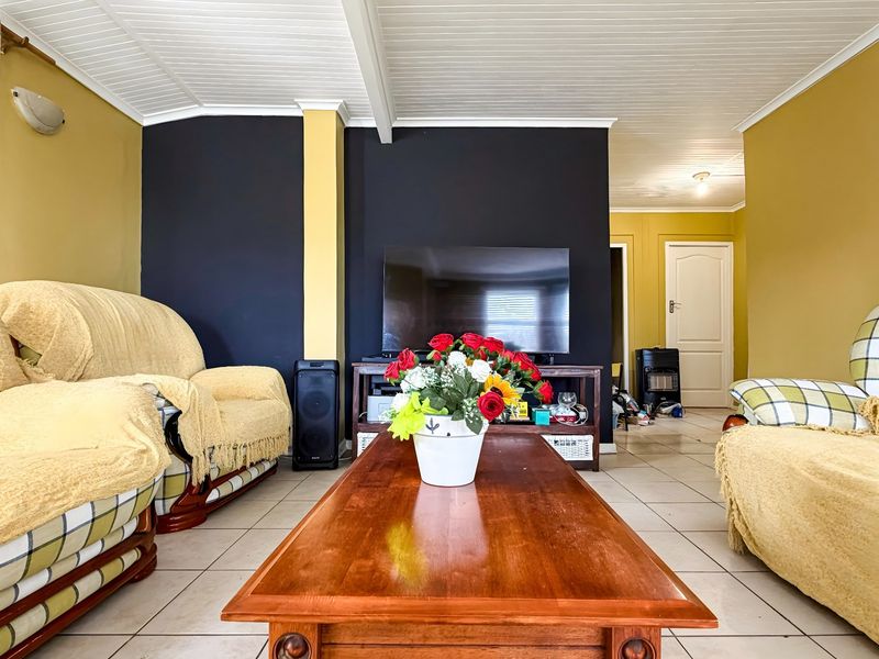 A living room featuring tiled flooring and a beadboard ceiling, with a neutral layout and direct access to adjacent rooms.