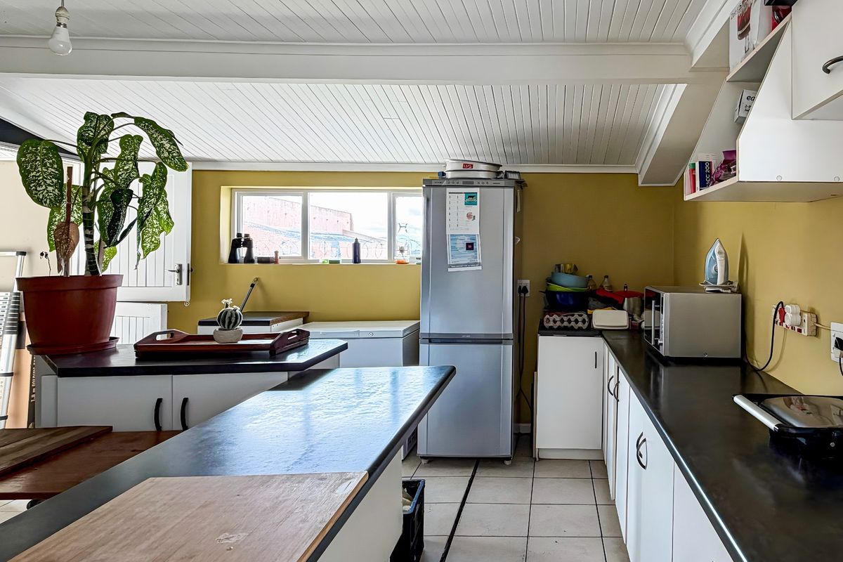 Functional kitchen featuring white cabinetry, dark laminate countertops, tiled flooring, and a distinctive white tongue and groove ceiling.
