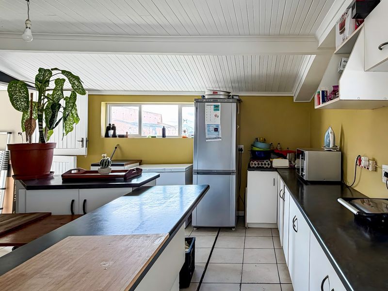 Functional kitchen featuring white cabinetry, dark laminate countertops, tiled flooring, and a distinctive white tongue and groove ceiling.
