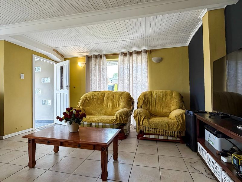 A living room featuring tiled flooring and a white beaded timber ceiling, providing a functional space with direct access to the exterior.