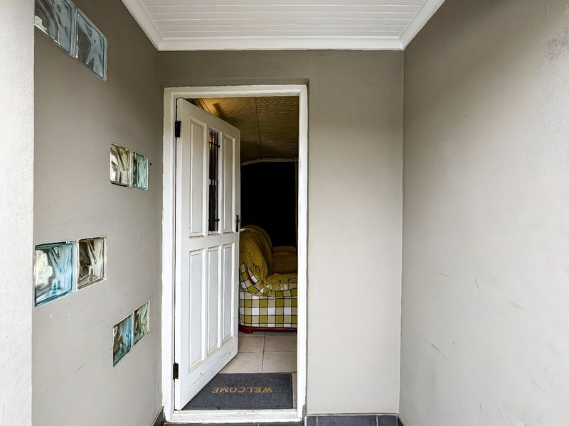 An entrance area featuring a panelled door, decorative glass block wall inserts, and a tongue and groove ceiling.
