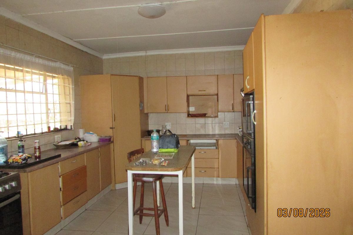 A dated kitchen featuring built-in cabinetry, tiled flooring, and a tiled backsplash, offering a functional layout with potential for modern renovation.