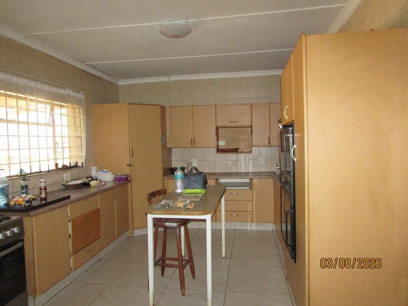 A dated kitchen featuring built-in cabinetry, tiled flooring, and a tiled backsplash, offering a functional layout with potential for modern renovation.