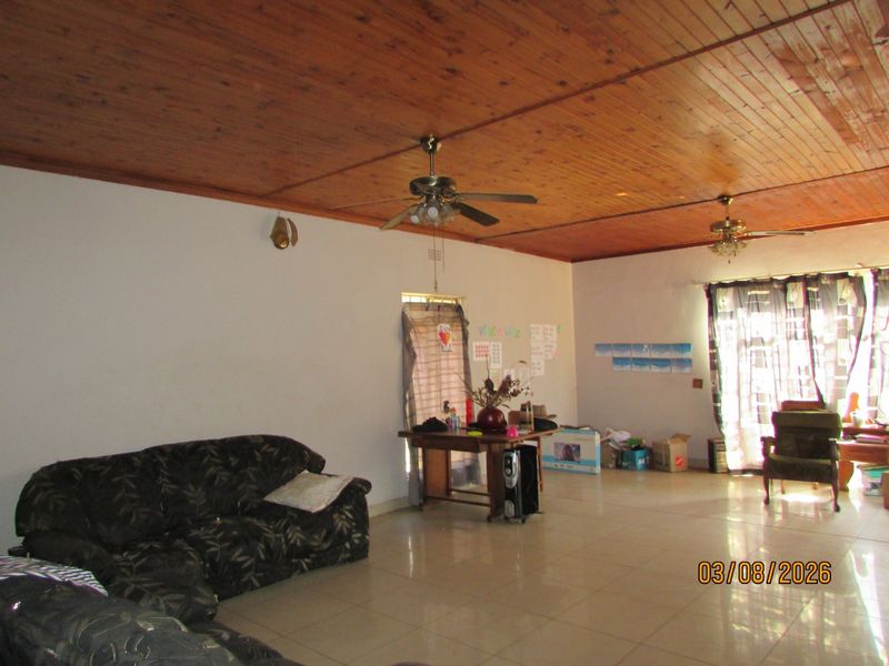 Spacious living area featuring a timber tongue and groove ceiling, tiled flooring, and access to the outdoors via a sliding glass door.