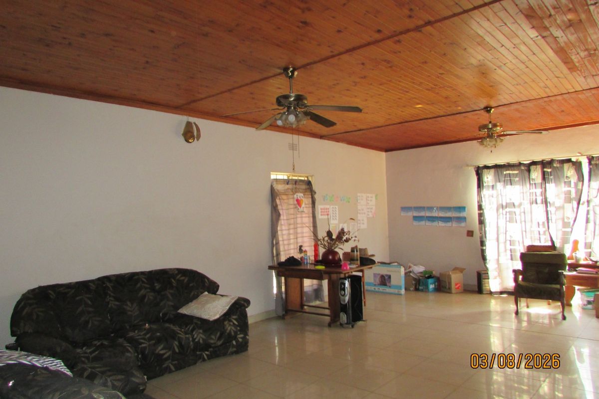 Spacious living area featuring a timber tongue and groove ceiling, tiled flooring, and access to the outdoors via a sliding glass door.