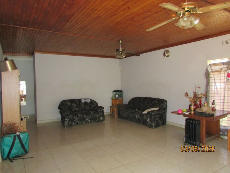 Spacious living area featuring tiled flooring and a traditional timber tongue and groove ceiling with dual ceiling fans.