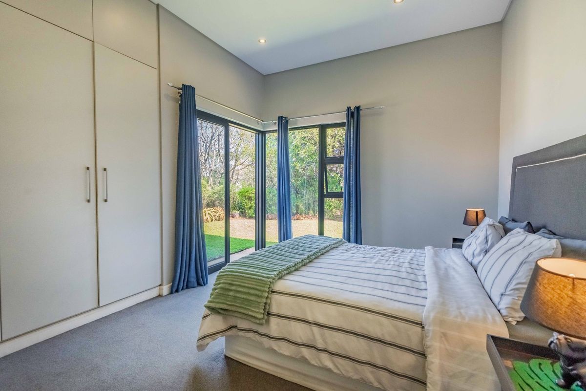 A well-maintained bedroom featuring built-in cupboards, carpeted flooring, and corner sliding glass doors providing direct access to the garden.