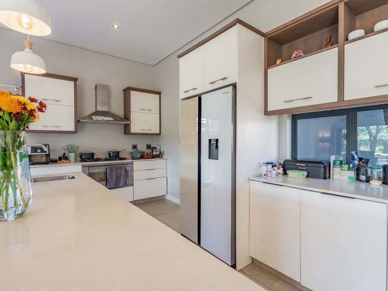 Modern kitchen featuring a large island with quartz countertops, sleek built-in cabinetry, integrated appliances, and contemporary pendant lighting.