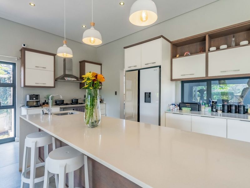 Modern kitchen featuring a large central island with quartz countertops, sleek built-in cabinetry, high-end appliances, and stylish pendant lighting.