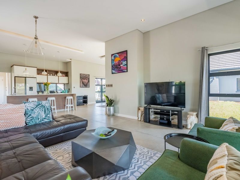 Spacious open-plan living area featuring a modern kitchen with island, tiled floors, and large windows providing ample natural light.