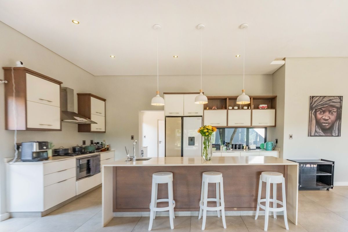 Modern kitchen featuring a central island with breakfast bar seating, built-in oven, extractor fan, and ample cabinetry with sleek finishes.