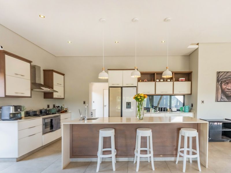 Modern kitchen featuring a central island with breakfast bar seating, built-in oven, extractor fan, and ample cabinetry with sleek finishes.