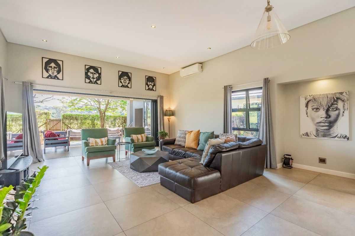 Spacious living room featuring large format floor tiles, recessed lighting, and wide stacking glass doors that open onto an outdoor patio area.