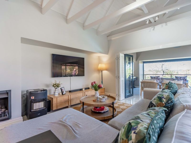 Spacious living room featuring a vaulted ceiling with exposed rafters, a built-in fireplace, and bi-fold doors leading to an outdoor balcony area.