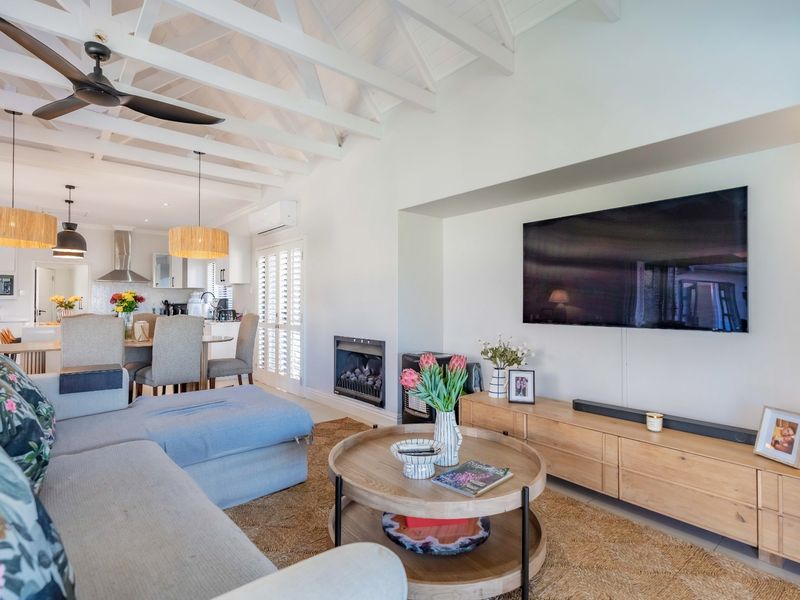Bright open-plan living and dining area featuring exposed white timber beams, a built-in fireplace, and seamless flow into a modern kitchen.