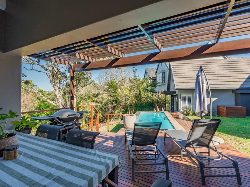Covered timber deck patio featuring a pergola, overlooking a private swimming pool and landscaped garden area.