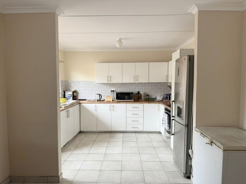 A functional kitchen featuring white cabinetry, subway tile backsplash, wooden countertops, and ceramic floor tiles, offering a clean and practical workspace.