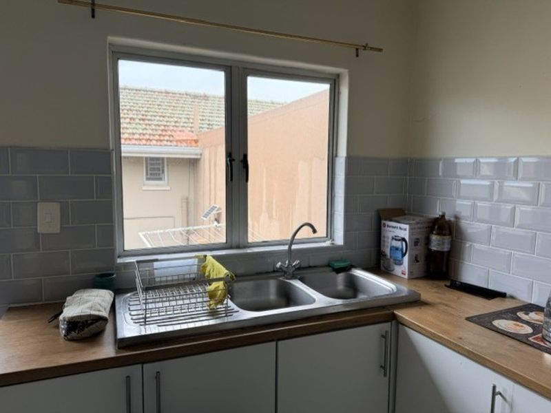 A functional kitchen area featuring a double bowl stainless steel sink, subway tile backsplash, and wood-look laminate countertops with ample built-in cabinetry.