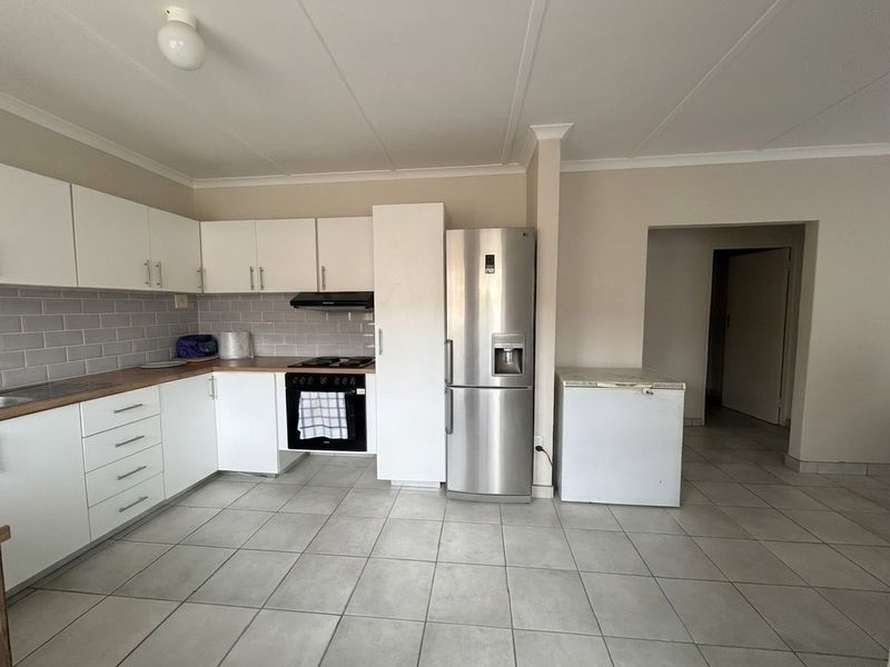 A functional kitchen featuring white cabinetry, wood-look countertops, subway tile backsplash, and built-in oven with extractor fan, finished with neutral floor tiles.