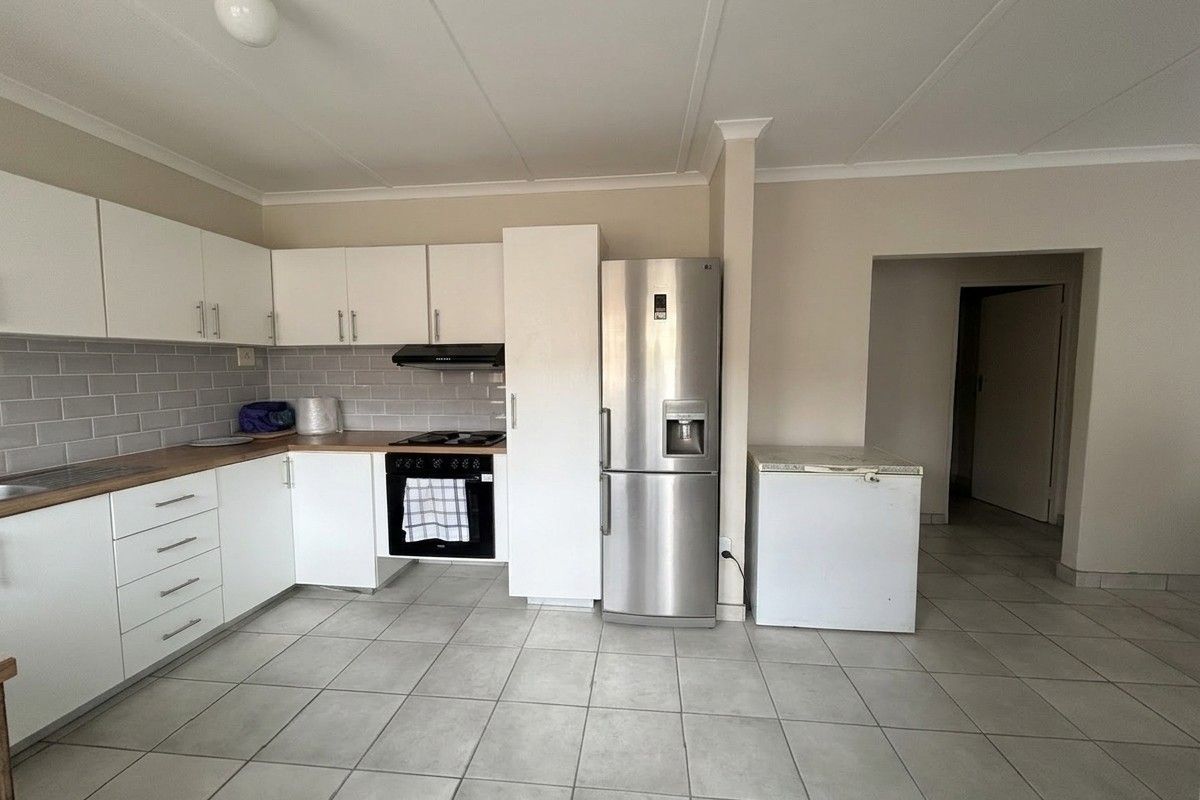 A functional kitchen featuring white cabinetry, wood-look countertops, subway tile backsplash, and built-in oven with extractor fan, finished with neutral floor tiles.